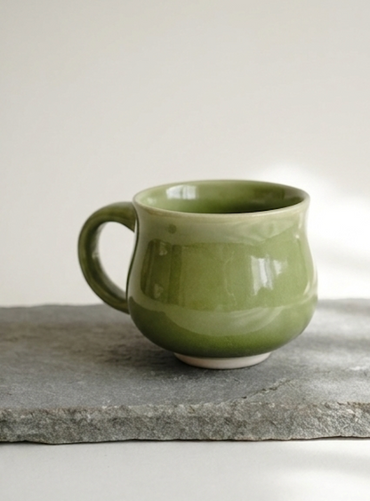 Round, bulbous sage green stoneware teacup with a small handle Ceramics By Marla.